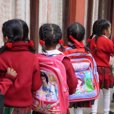 Students in Nepal wait patiently in a line for their Childcare volunteer Children line up with their backpacks outside their classroom in Nepal